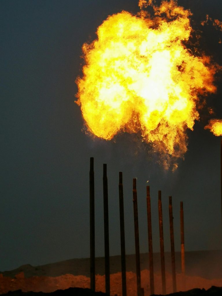 Intense gas flare at night illuminating industrial towers in Arumel, Iraq refinery.